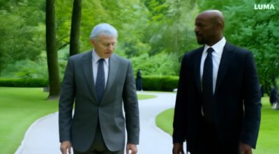 man with gray hair wearing a suit, walks in the park and meet someone exactly like him and they shake hands-597650